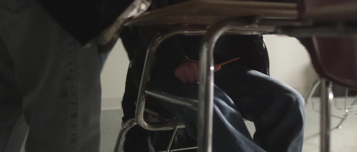 Two boys bullying another boy sitting in a classroom