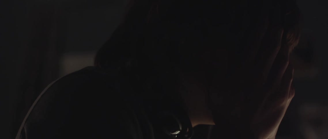 A man sits in the dark with his face in his hands and cries