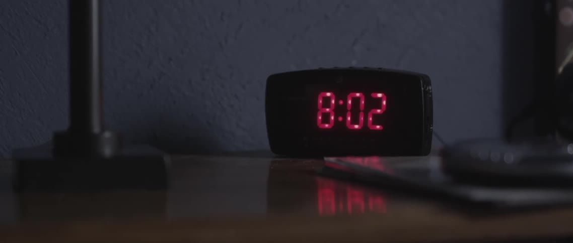 Digital clock on nightstand reads 802 in read numbers