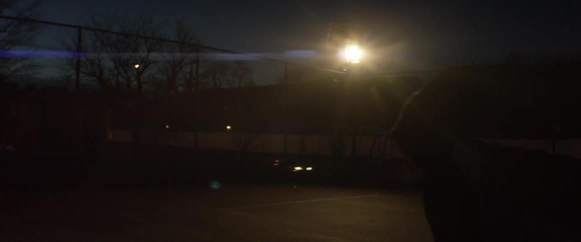A man dribbles a basketball on an outdoor court at night