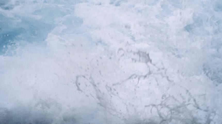 A still shot of ocean waves crashing over one another in splashes of white foam