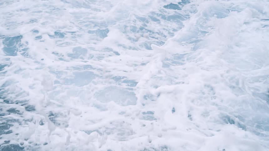 Waves crashing on the ocean surface creating white foam and ripples over the surface