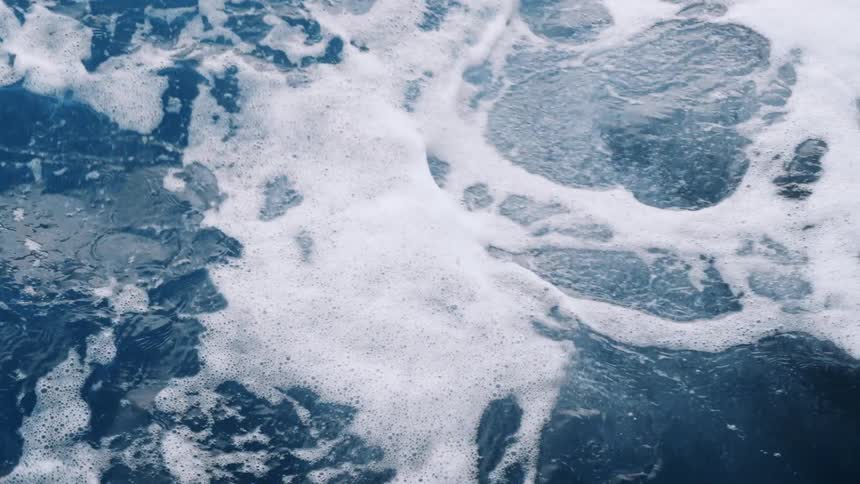 Ocean waves push into each other as sea foam bubbles up from the movement