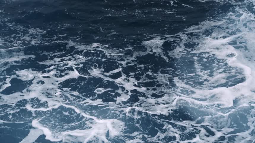 Aerial straight down of ocean waves crashing and rolling over each other creating a foamy substance
