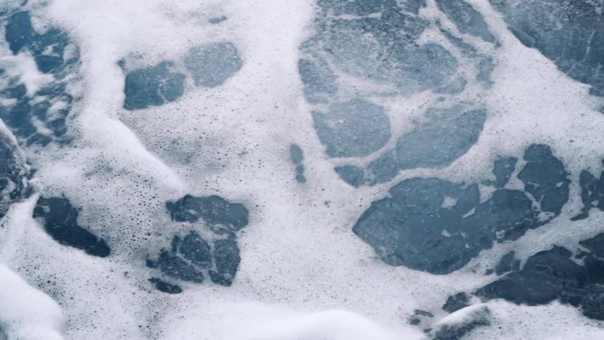 Sea foam kicks up as ocean waves crash into each other