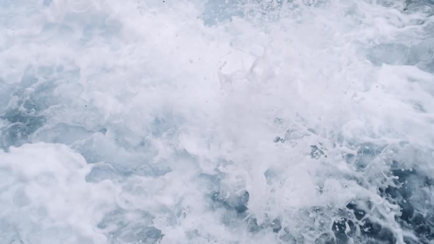 White waves are crashing over a bunch of rocks in the sea along the coast