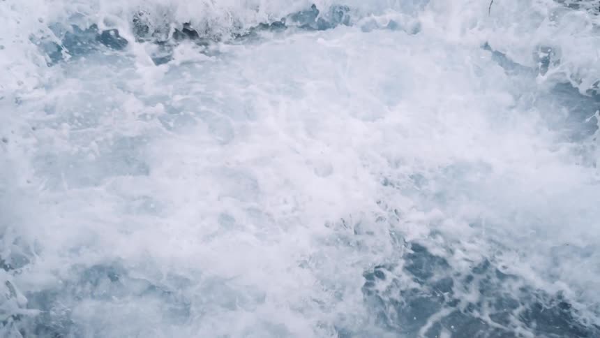 Ocean waves crashing into rocks is displayed