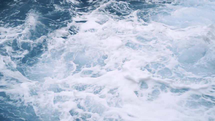 Sea foam bubbles up as ocean waves crash into each other