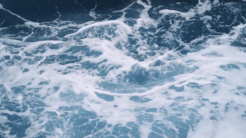 Drone view straight down of waves on the ocean crashing and foaming on the surface