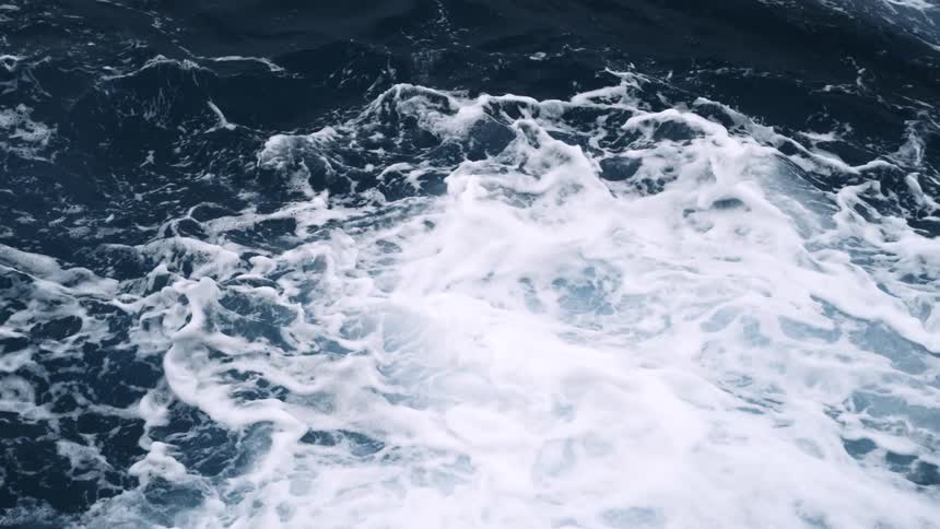 Ocean waves crashing against a surface splashing up and creating foam over the surface