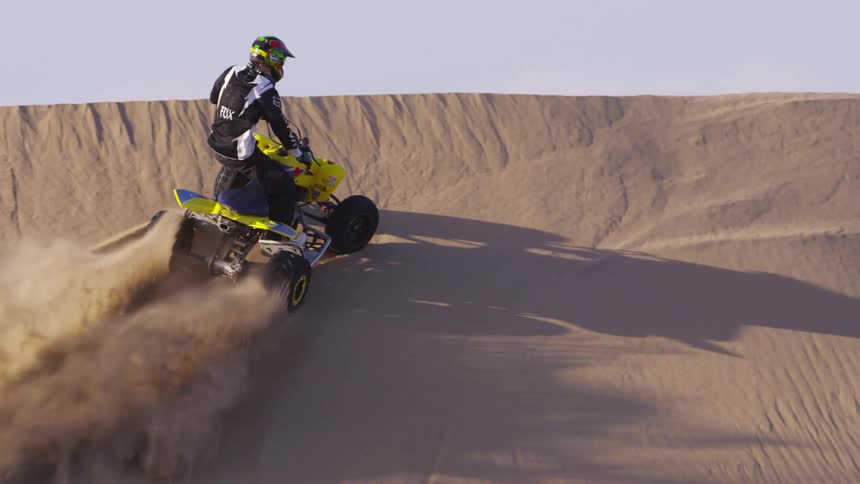 A person is driving up a sand dune