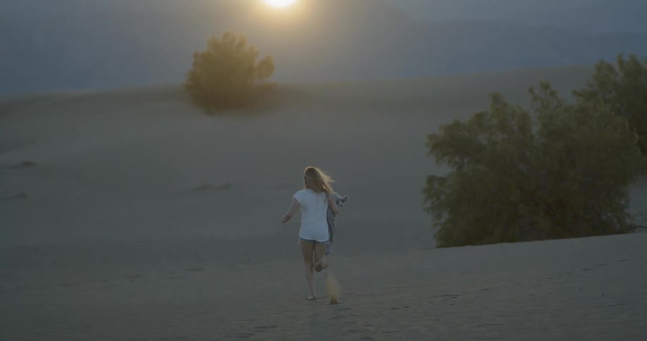 Woman running through a desert carry a blanket