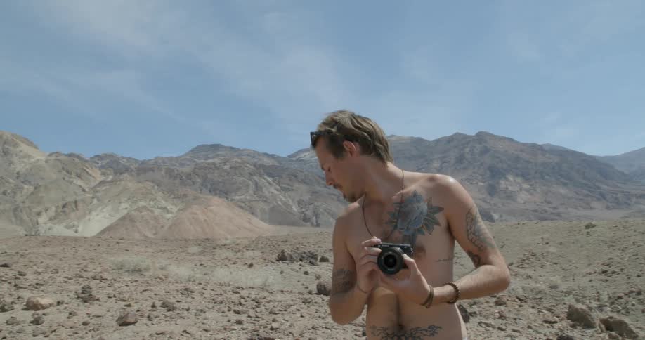 A man is taking photographs near a mountain range