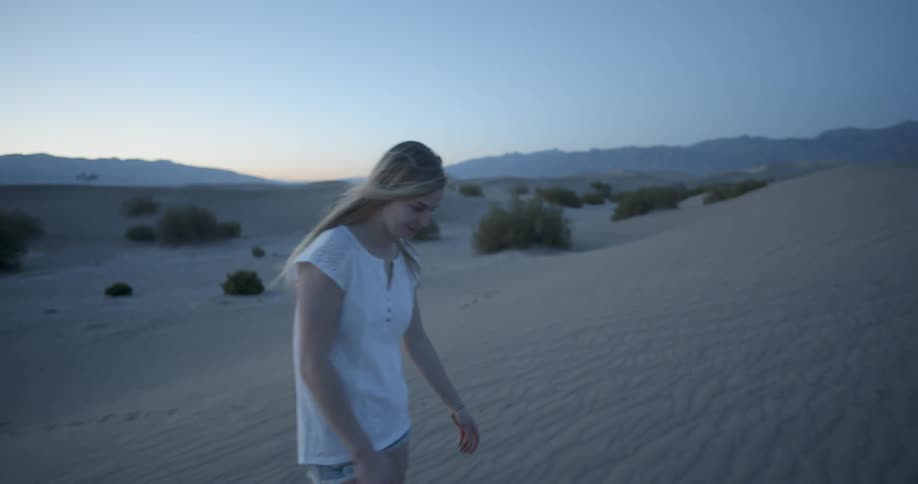 A woman walks in the desert talking and smiling
