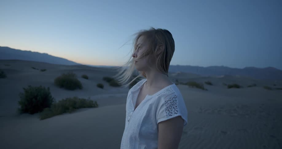 A woman is walking in the desert on a windy day