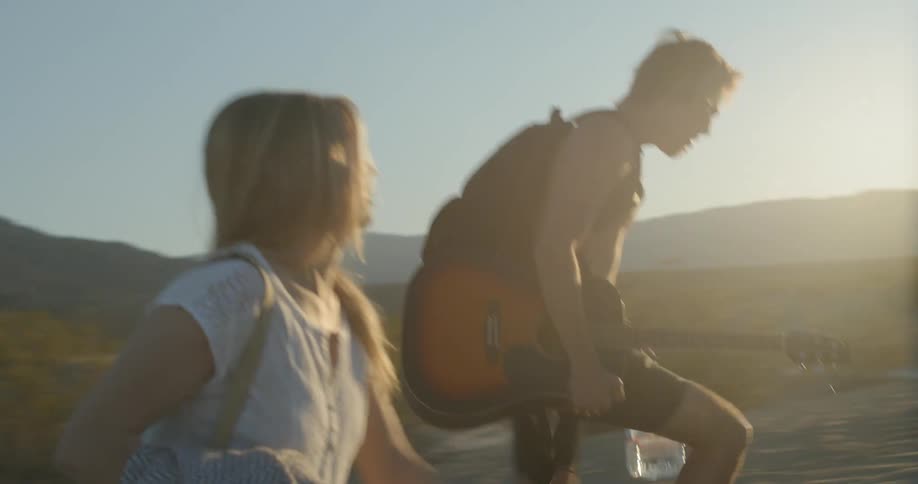 A man holding a guitar and a woman walk uphill
