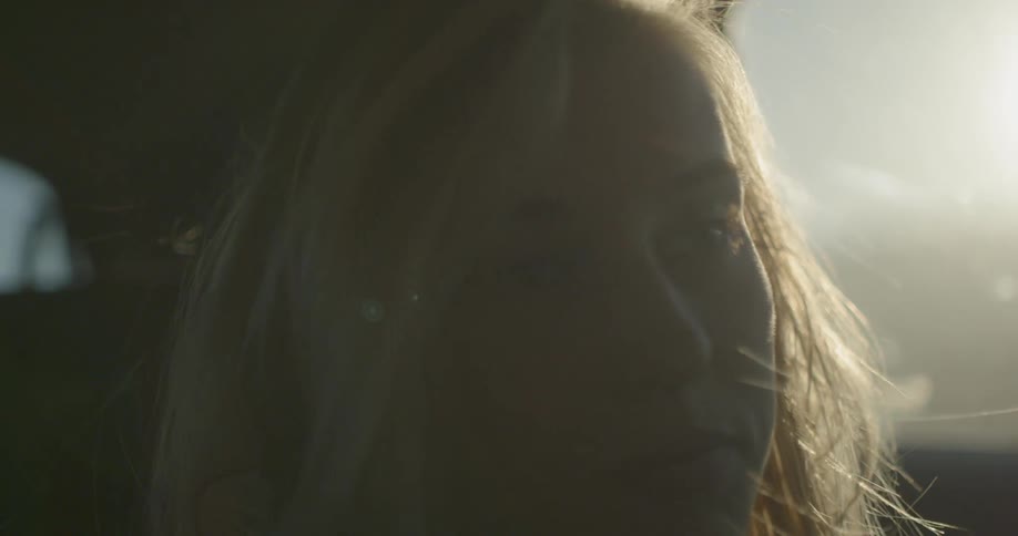 Woman rides in a vehicle with sun shining in the window