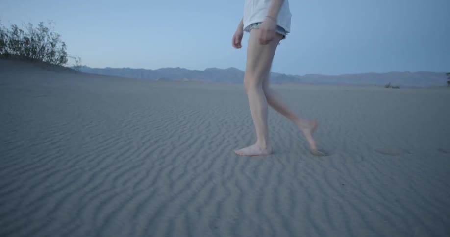 A woman is walking on the sand on a clear day