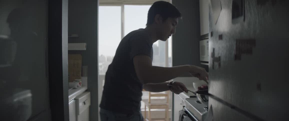 A man cooks on a stove in a galley style kitchen