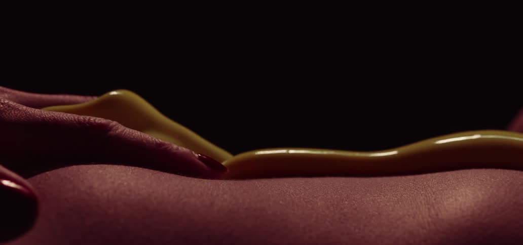 A womans hand rubbing across her body with a yellow gel running towards her fingers