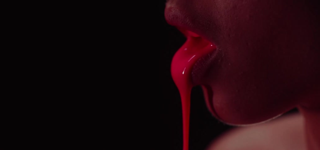 A red liquid drips from a womans mouth