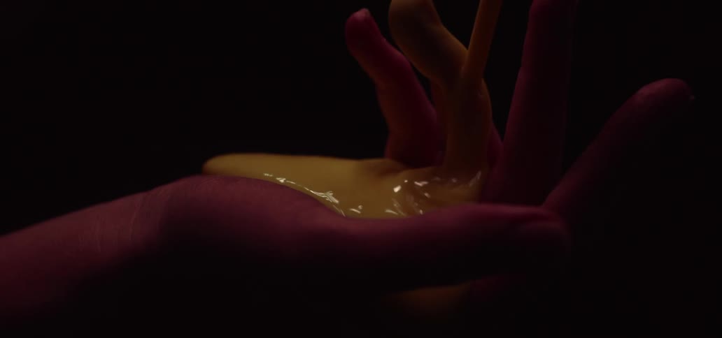 Yellow mustard is poured into a womans hand and she closes her palm around it as it spills over
