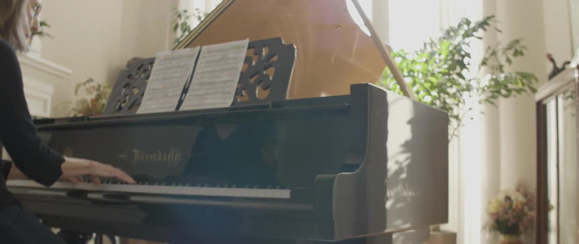 A woman is playing fast on a piano