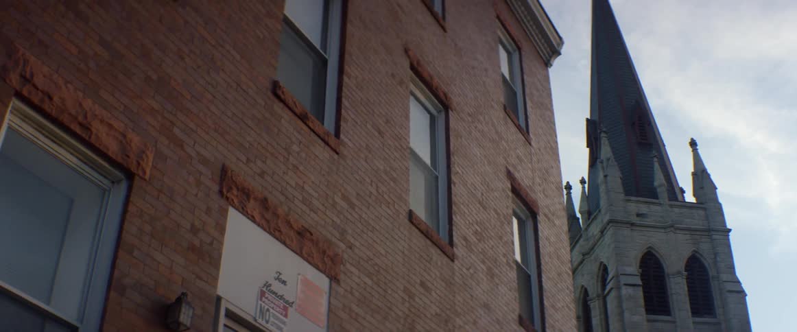 A brick building and church steeple tower overhead