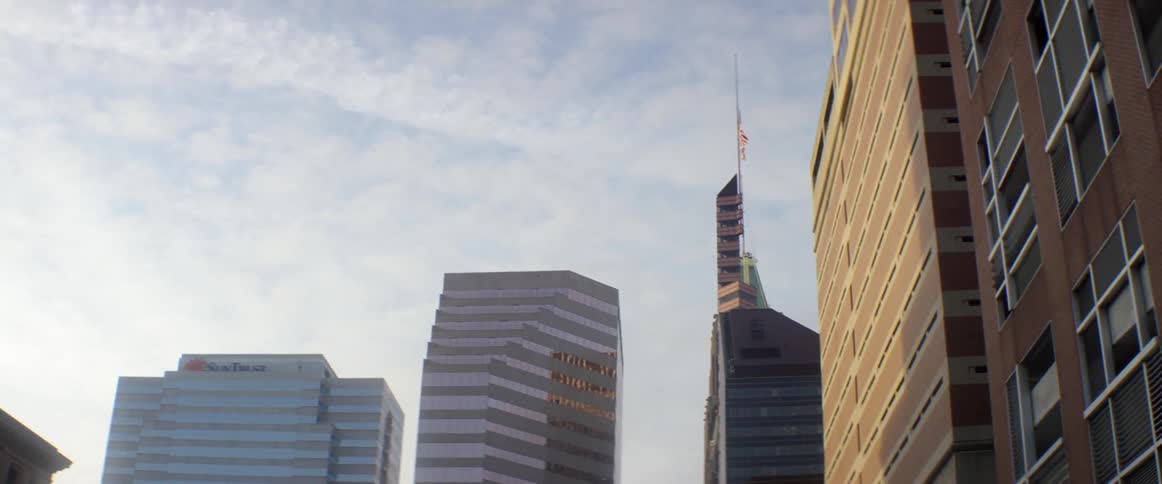 An american flag waves in the breeze at the top of a high rise