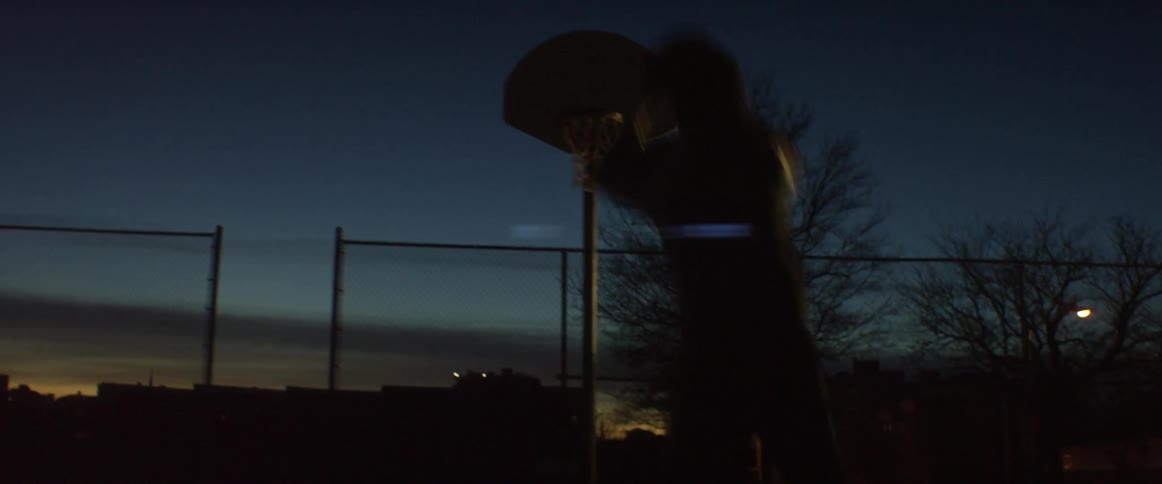 A man is shooting a basketball at dawn