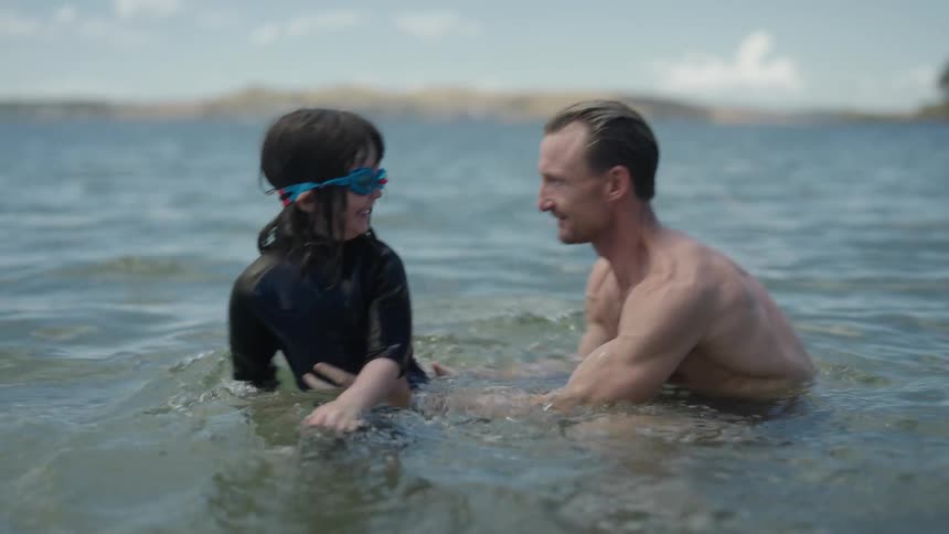 The view is of a portrait of a father and kid that is swimming in the ocean