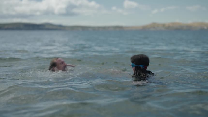 Father and daughter are swimming in the ocean