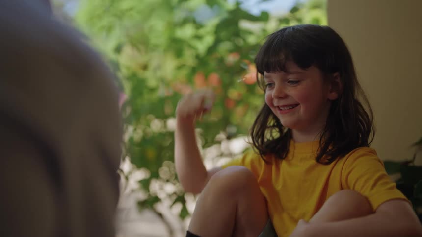 Daughter sitting on porch with father smiles and high fives him