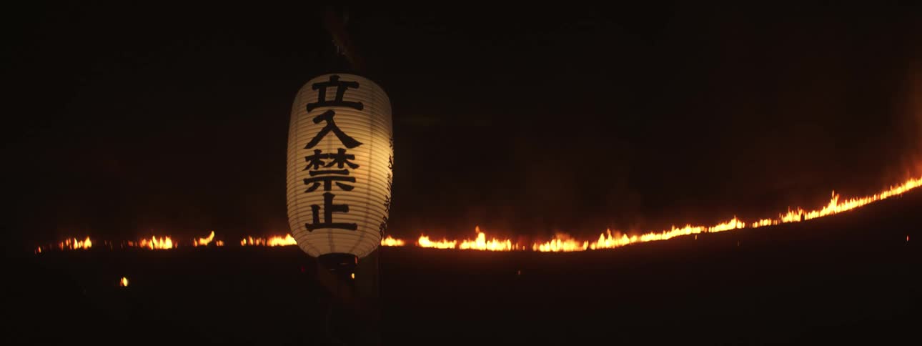 A lantern with writing on it in front of fire