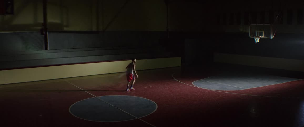 Man dribbling basketball towards hoop on basketball court