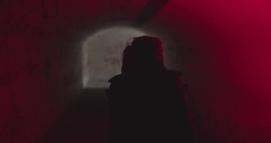 A woman walks down a hallway lit by red light