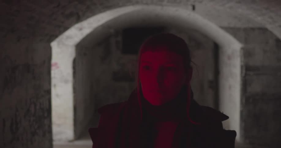 A woman walks through stone tunnels with windows