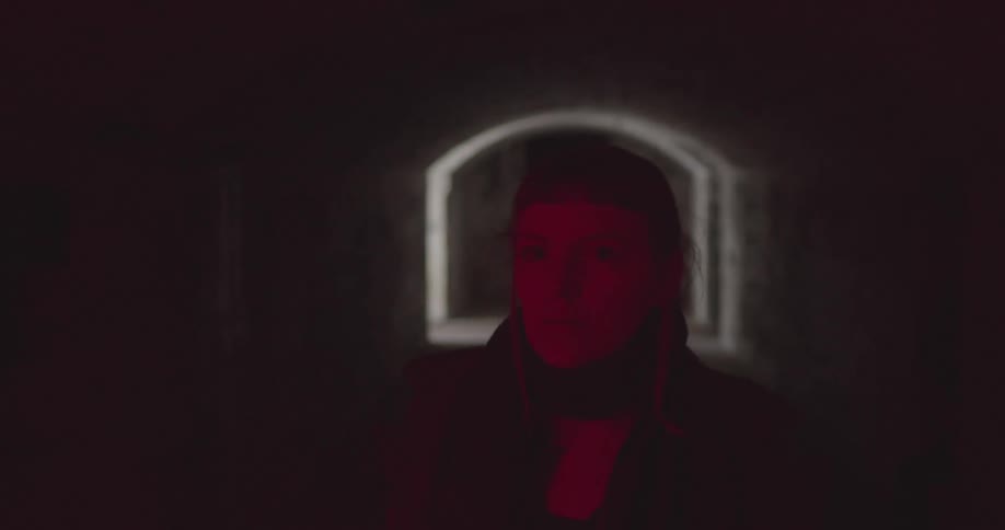 A white woman walks down a dark hallway