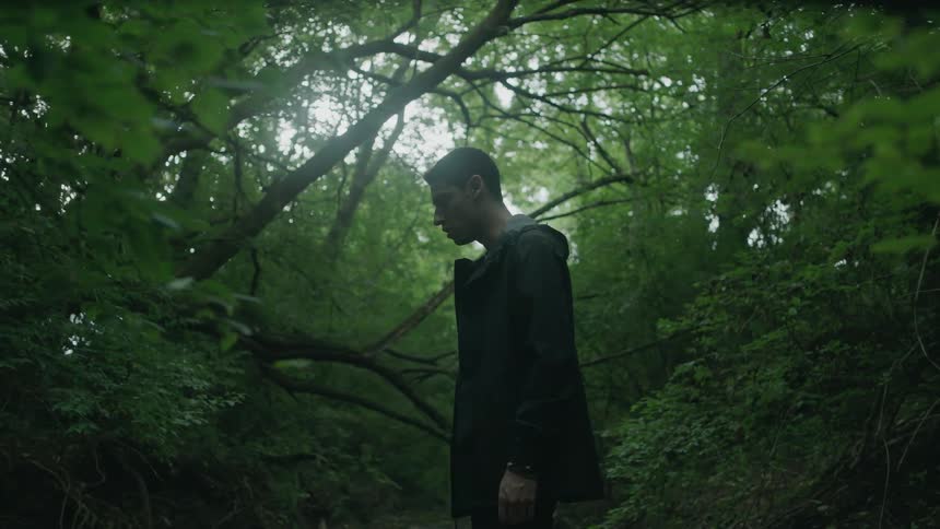 Man stands still looking up in the woods