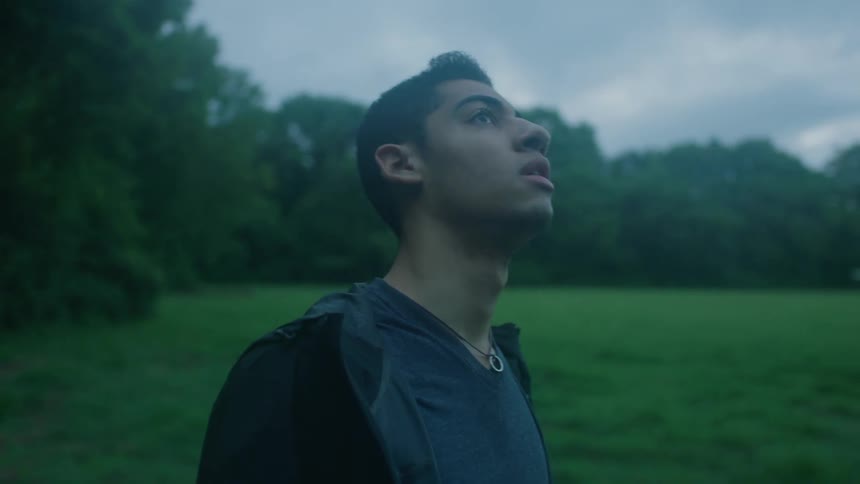A man in a black shirt stands in a clearing