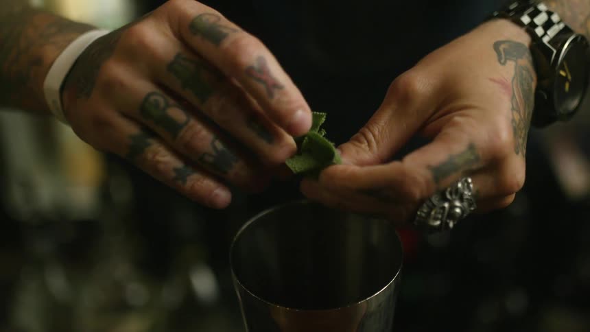 A person with rings and a wristwatch in a bar ripping a cloth and place in it into a cup