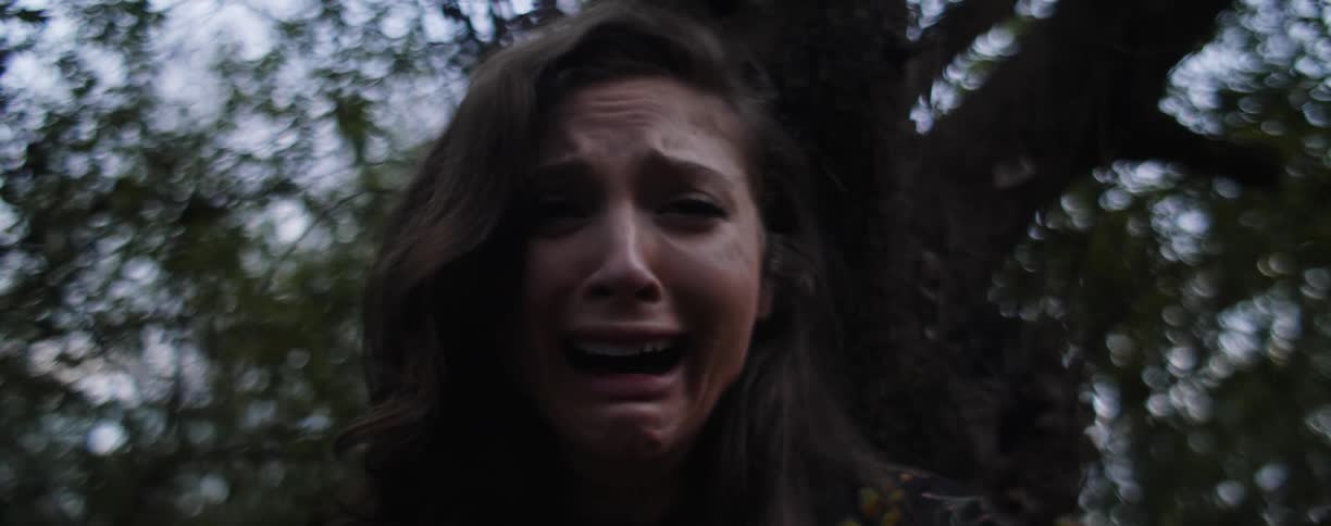 A woman weeps and cries under a tree