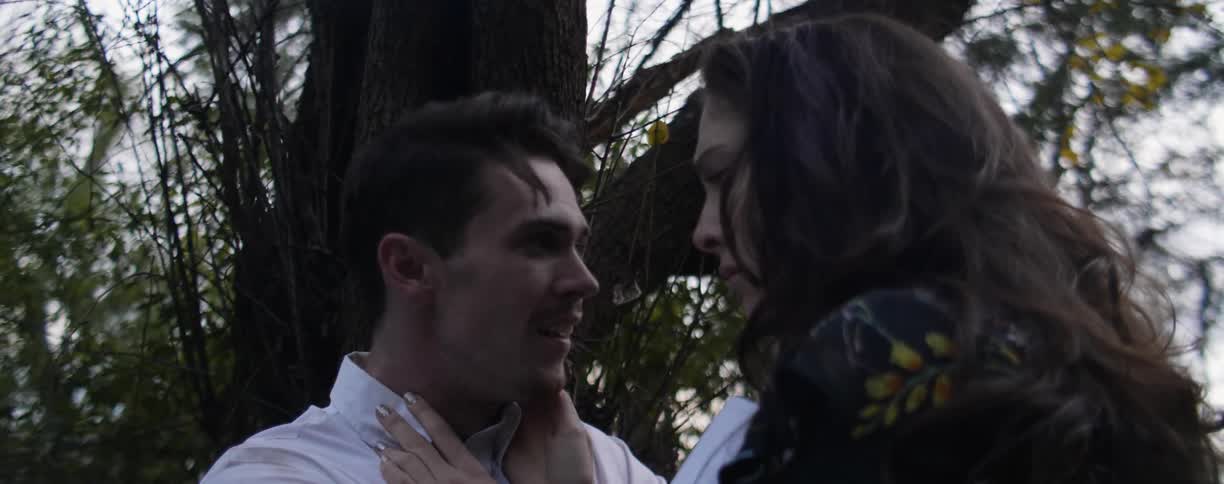 A man and woman talk passionately under a tree