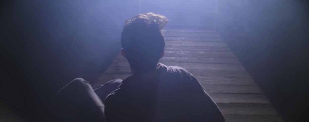 A sleeping man in blue pajamas wakes up and walks toward the light