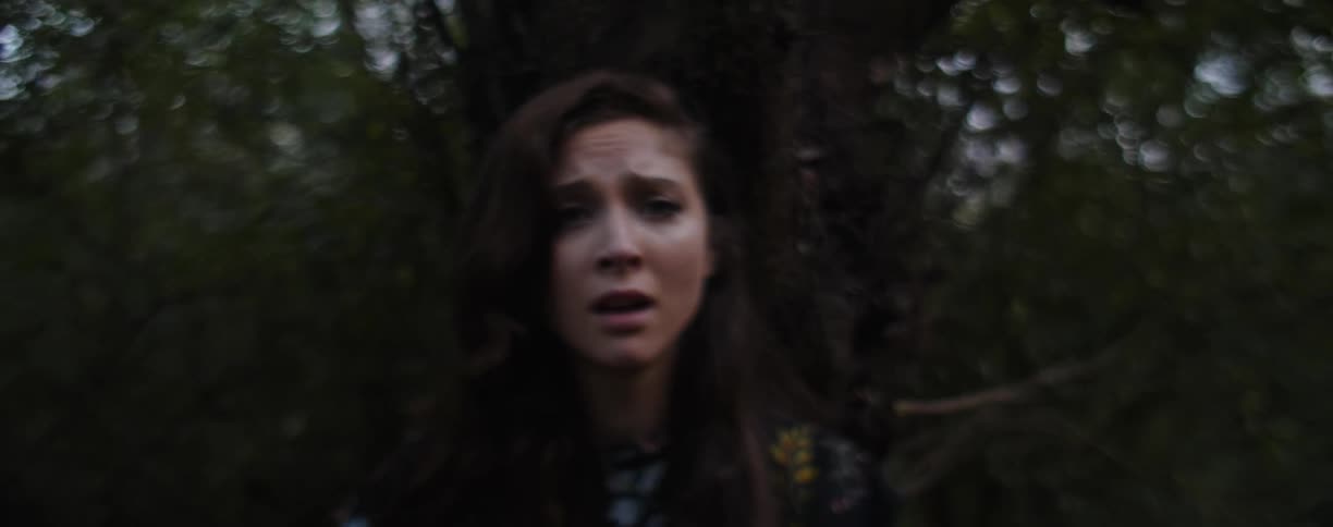 A woman with a worried look on her face next to a tree