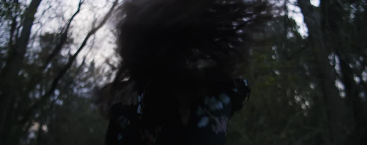 A woman runs through a forest laughing
