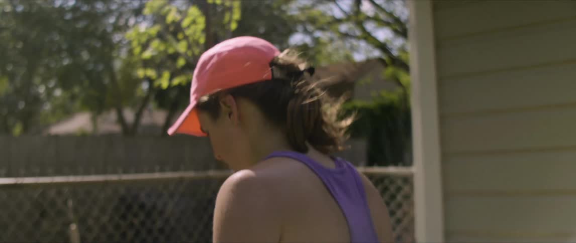 A woman walking outside to grab someone near a fence at their home