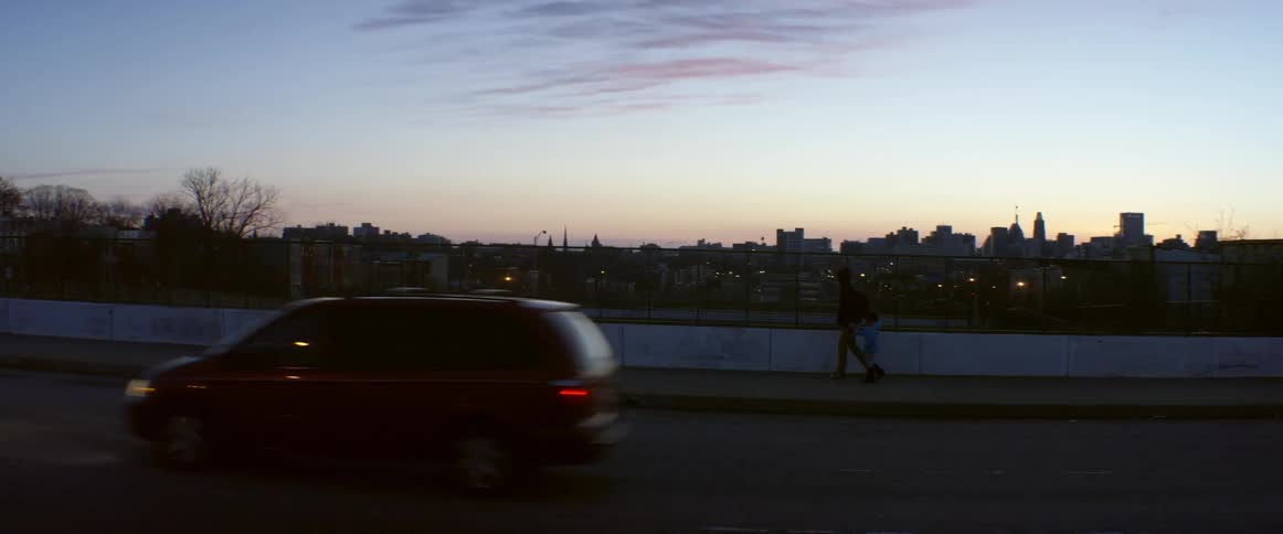 A man and child walk on an overpass at dawn