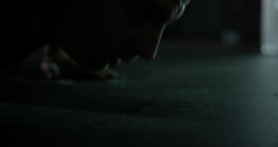 A man is doing push ups in a dark room