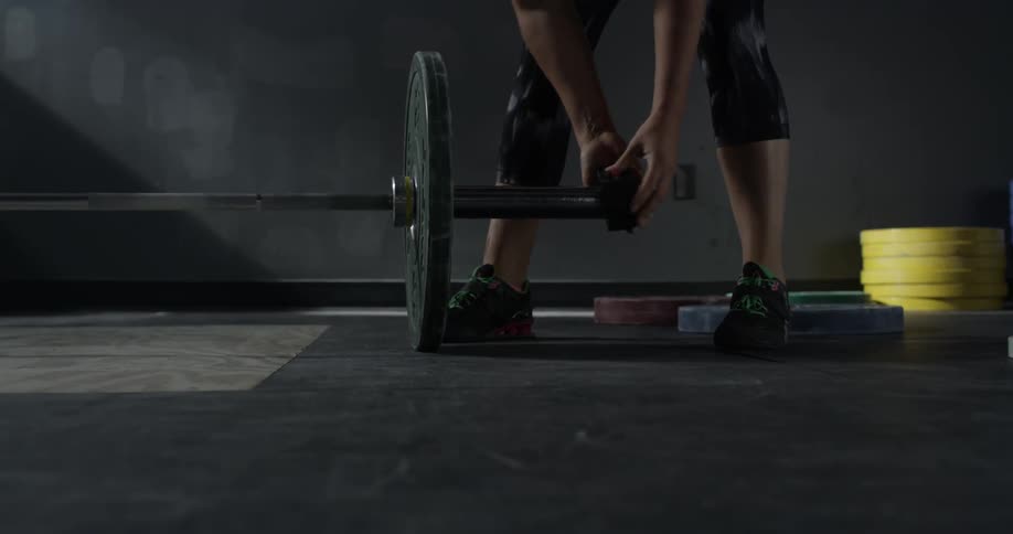 A woman attaches a weight to a barbell